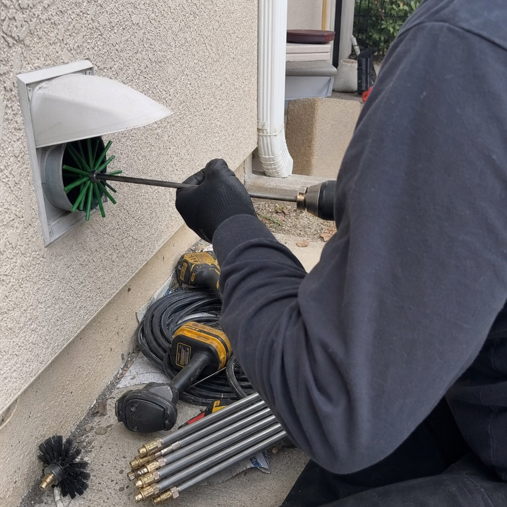 Technician performing professional dryer vent cleaning using a rotary brush tool